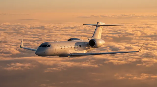 A white private jet in flight above golden clouds at sunset